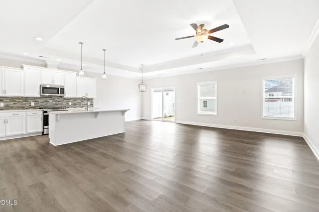 a view of a kitchen with a stove cabinets a ceiling fan and wooden floor