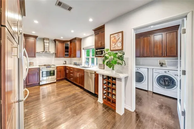 a view of kitchen with stainless steel appliances granite countertop a stove and a wooden floors