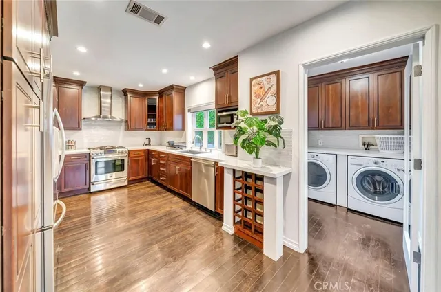 a view of kitchen with stainless steel appliances granite countertop a stove and a wooden floors