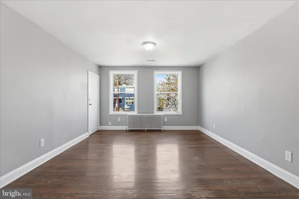 a view of an empty room with wooden floor and window