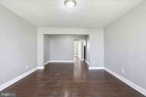 a view of an empty room with wooden floor and windows