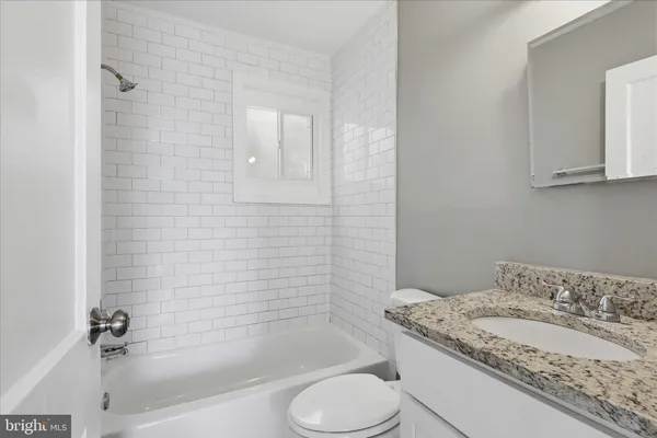 a bathroom with a granite countertop sink toilet and bathtub