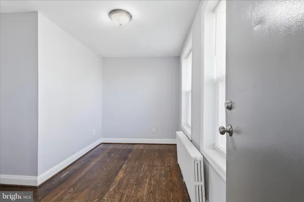 a view of a hallway with wooden floor and a bathroom