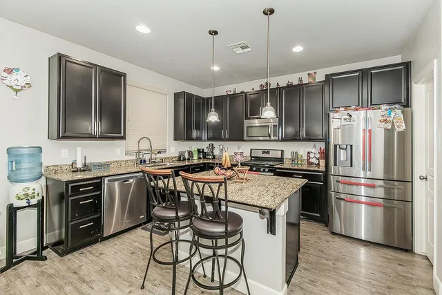 a kitchen with stainless steel appliances granite countertop a stove top oven a refrigerator a sink and dishwasher