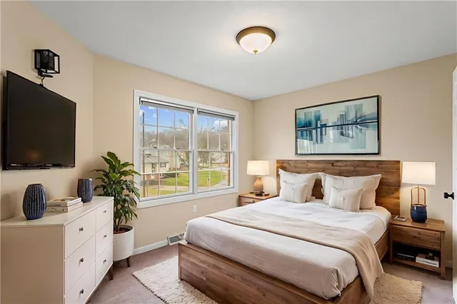 a bedroom with a large bed and a flat tv screen on dresser