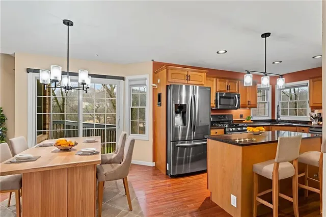 a kitchen with stainless steel appliances a dining table chairs a refrigerator and chandelier