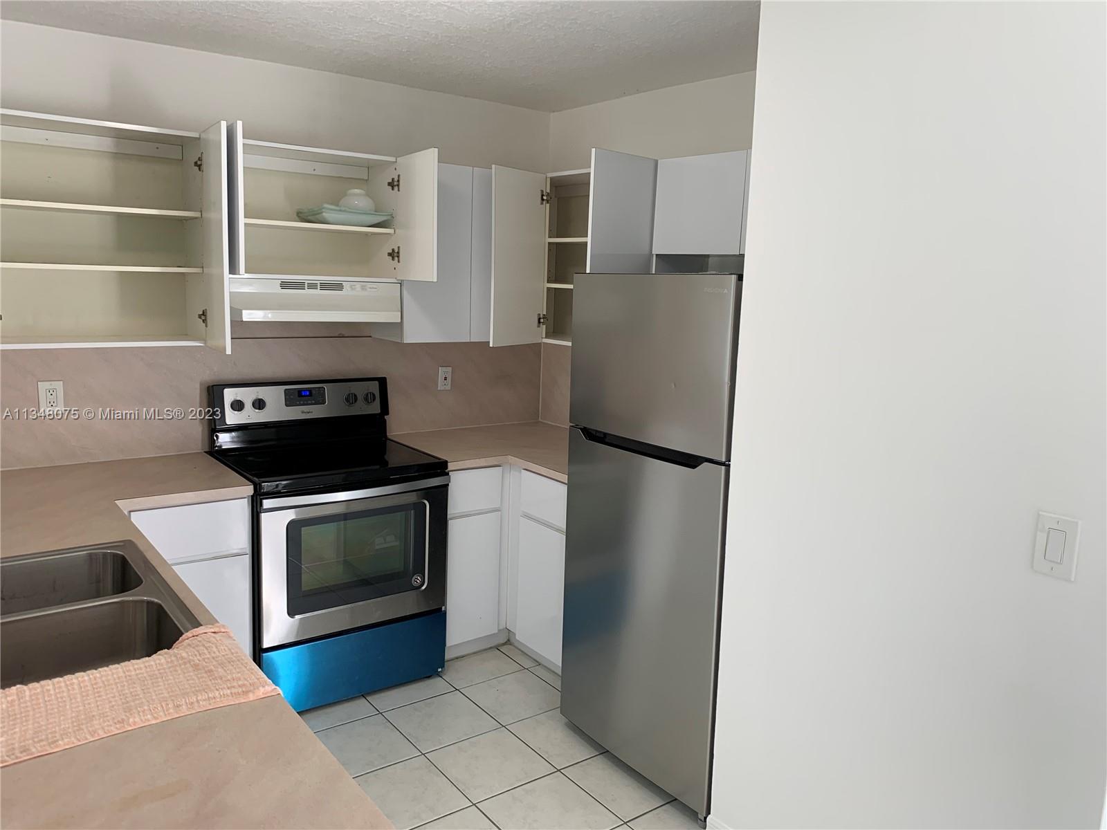 1016 Southwest 8th Street Hallandale Beach, FL 33009 - Photo 12 of 18 a kitchen with a refrigerator and a stove top oven