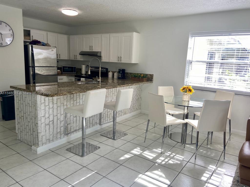 1016 Southwest 8th Street Hallandale Beach, FL 33009 - Photo 6 of 18 a kitchen with stainless steel appliances granite countertop a stove a refrigerator a white table and chairs