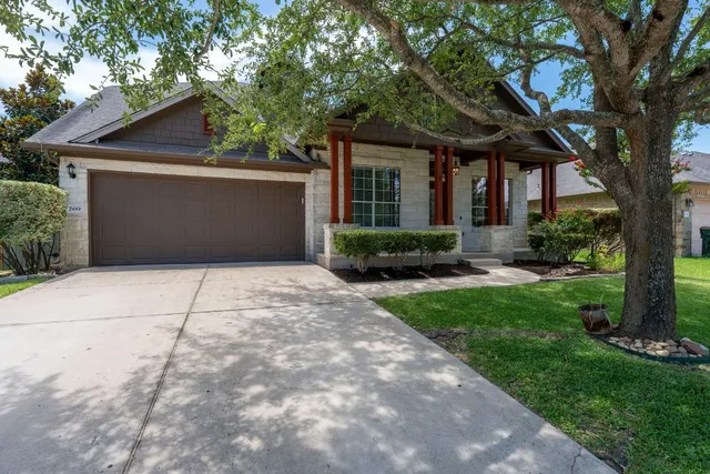 a front view of a house with a garden and trees