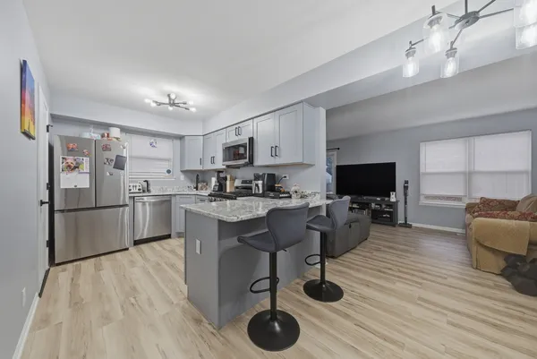 a kitchen with stainless steel appliances a stove a sink a refrigerator cabinets and a dining table