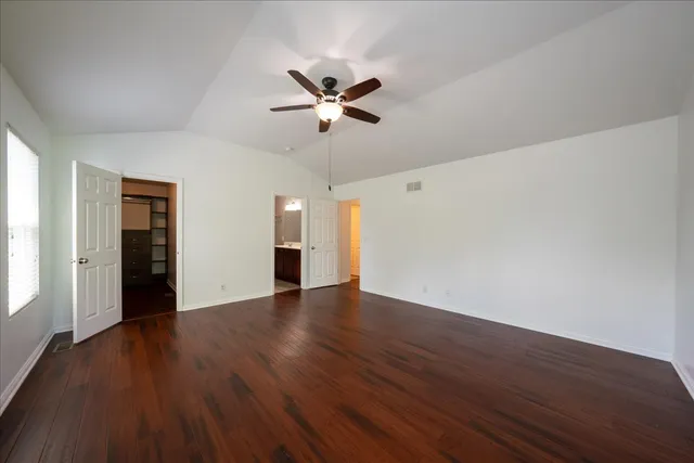 a view of an empty room with window and wooden floor