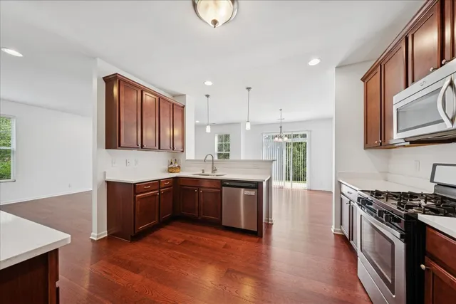 a large kitchen with stainless steel appliances granite countertop a stove top oven a sink dishwasher a dining table and chairs with wooden floor