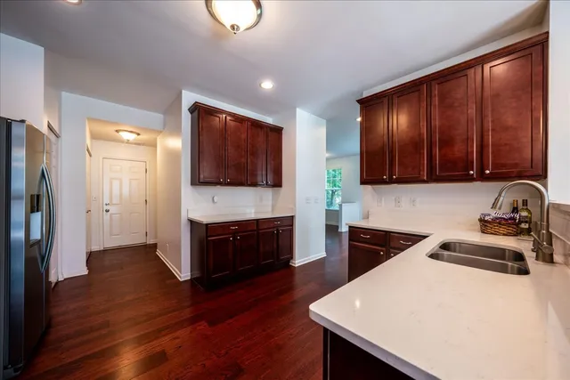 a kitchen with stainless steel appliances a sink a stove a refrigerator cabinets and wooden floor