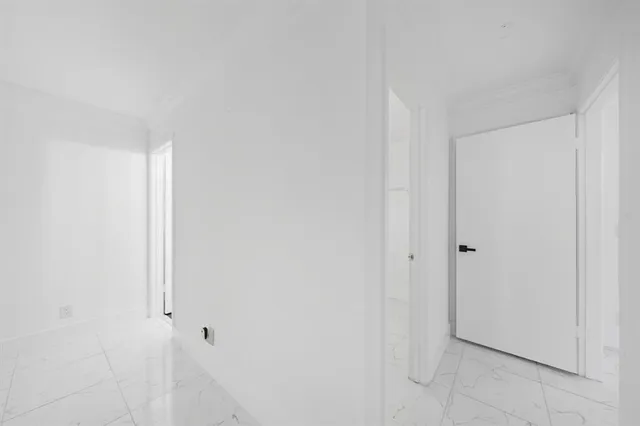 an empty room with chandelier fan and windows