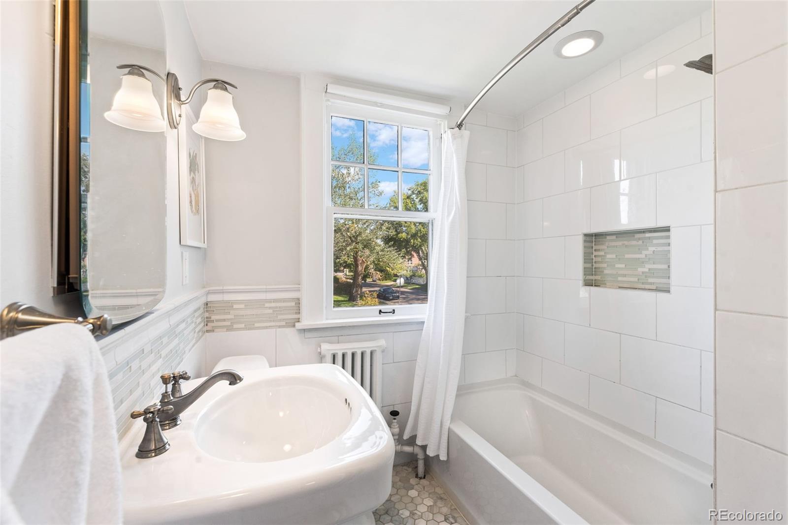 1205 Niagara Street Denver, CO 80220 - Photo 24 of 38 a white bath tub sitting next to a white sink and a mirror