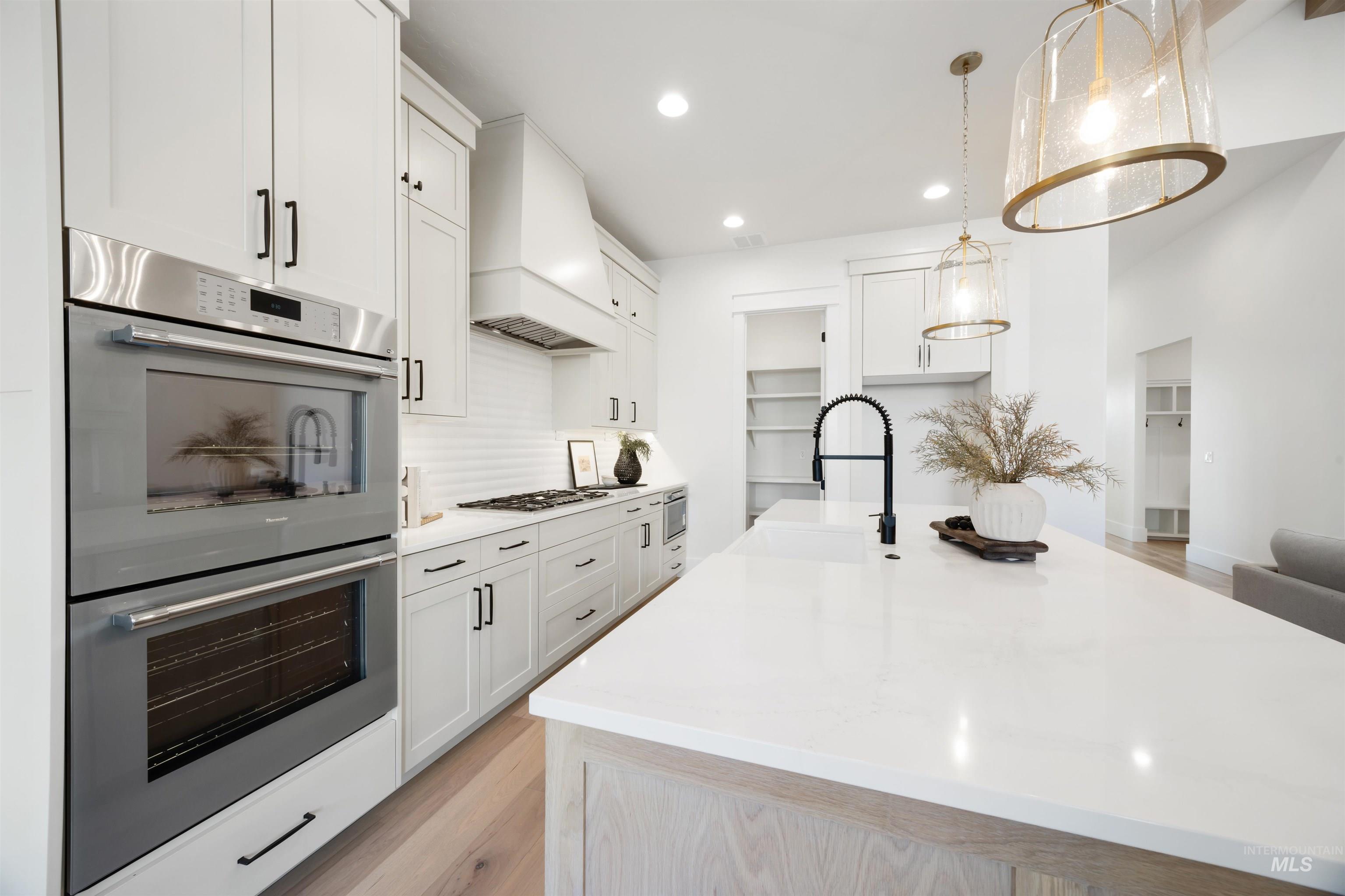 1034 East Escalation Street Meridian, ID 83642 - Photo 14 of 40 Kitchen featuring appliances with stainless steel finishes, light wood finished floors, light stone counters, recessed lighting, and decorative light fixtures
