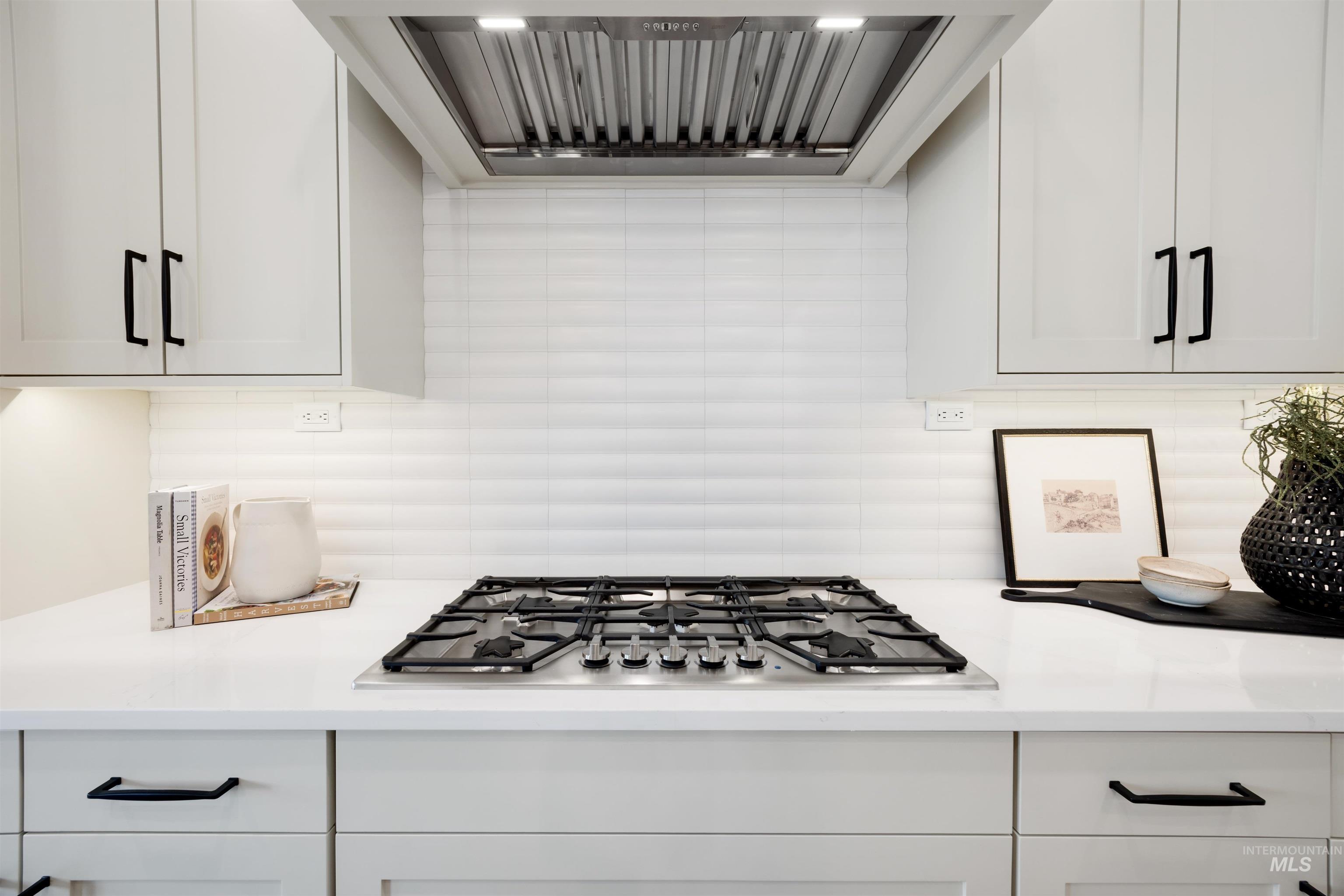 1034 East Escalation Street Meridian, ID 83642 - Photo 17 of 40 Kitchen with range hood, stainless steel gas stovetop, white cabinets, backsplash, and light stone counters