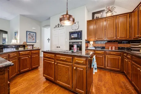 a kitchen with stainless steel appliances granite countertop a stove a sink dishwasher and a refrigerator with wooden floor