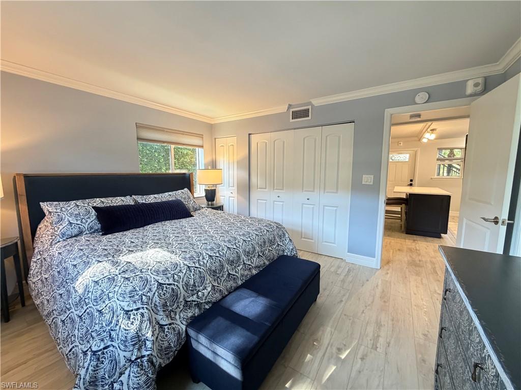 960 7th Street South, Unit 103 Naples, FL 34102 - Photo 16 of 16 a bedroom with a large bed and wooden floor