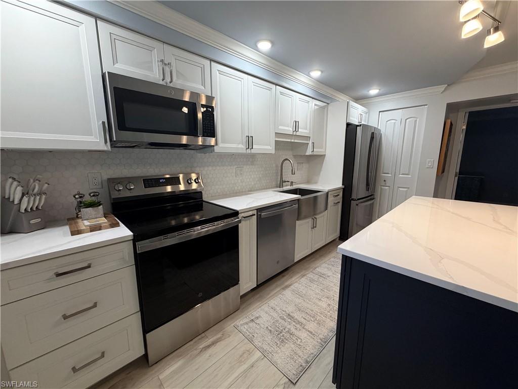 960 7th Street South, Unit 103 Naples, FL 34102 - Photo 7 of 16 a kitchen with stainless steel appliances a sink dishwasher a refrigerator a stove top oven a refrigerator and cabinets
