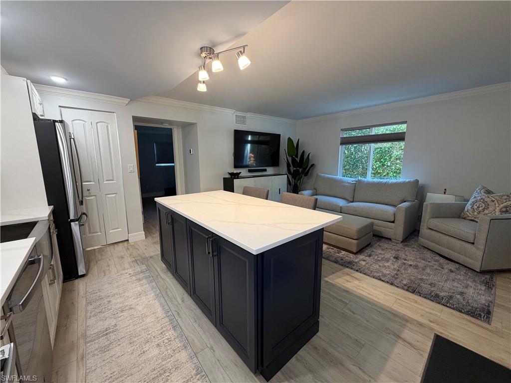 960 7th Street South, Unit 103 Naples, FL 34102 - Photo 8 of 16 a living room with stainless steel appliances granite countertop furniture and a flat screen tv