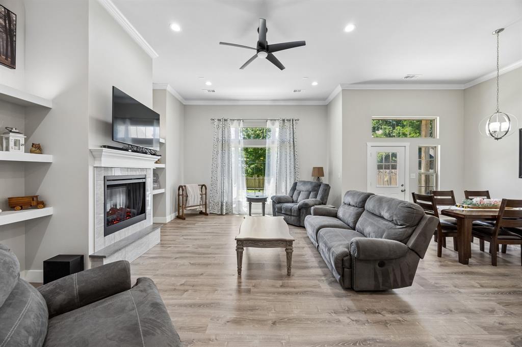 612 Frisco Road Sherman, TX 75090 - Photo 13 of 25 Open-concept living space featuring wood-finish flooring, a tiled fireplace with a white mantel, recessed lighting, and a ceiling fan