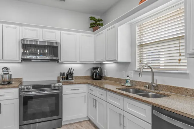 a kitchen with stainless steel appliances granite countertop white cabinets a sink and dishwasher