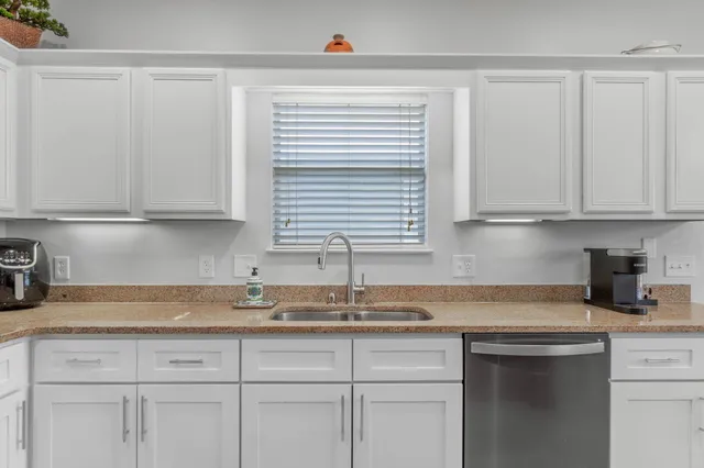 a kitchen with granite countertop white cabinets and a window