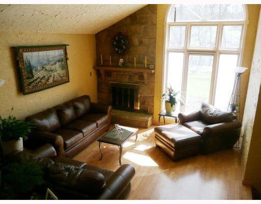 Living Room. Warm and Inviting with Stone fireplace and full palladium window.  Laminate wood flooring throughout living and dining room