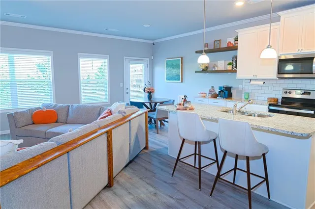 a kitchen with stainless steel appliances granite countertop a sink a stove a dining table and chairs