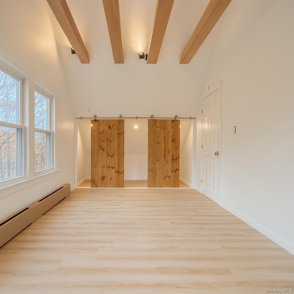 88 Cold Spring Road Liberty, NY 12754 - Photo 21 of 32 Top level room with baseboard heating, beamed ceiling, wood finished floors, a barn door, and high vaulted ceiling