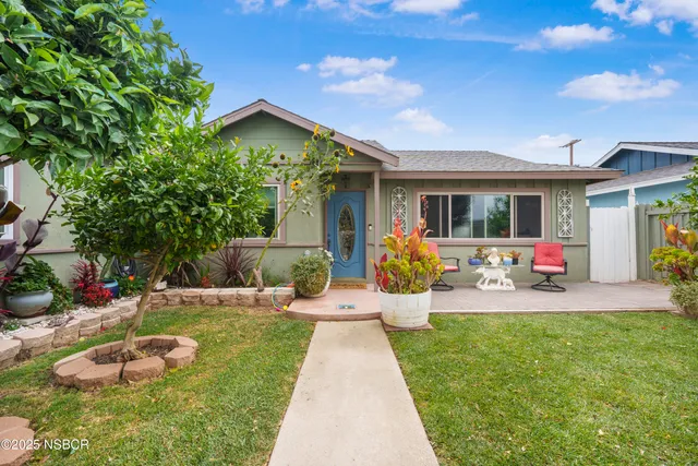 a view of a backyard with table and chairs potted plants and a large tree