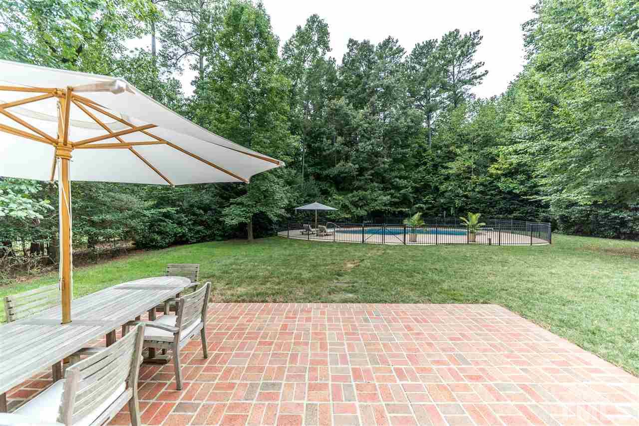 5233 Wildmarsh Drive Raleigh, NC 27613 - Photo 22 of 25 a view of a backyard with table and chairs under an umbrella