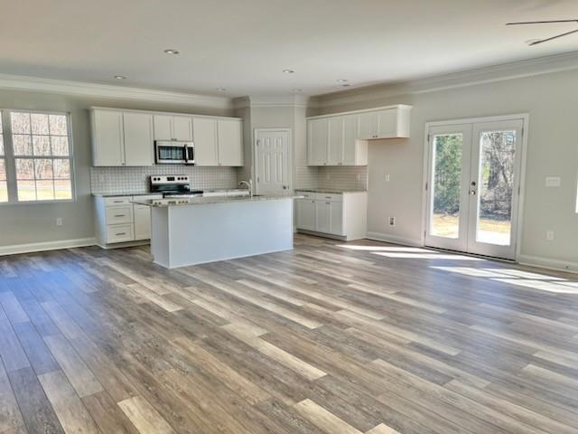 5322 Pond Bluff Drive Monroe, NC 28112 - Photo 4 of 21 a large white kitchen with kitchen island a sink wooden floor and a refrigerator in it