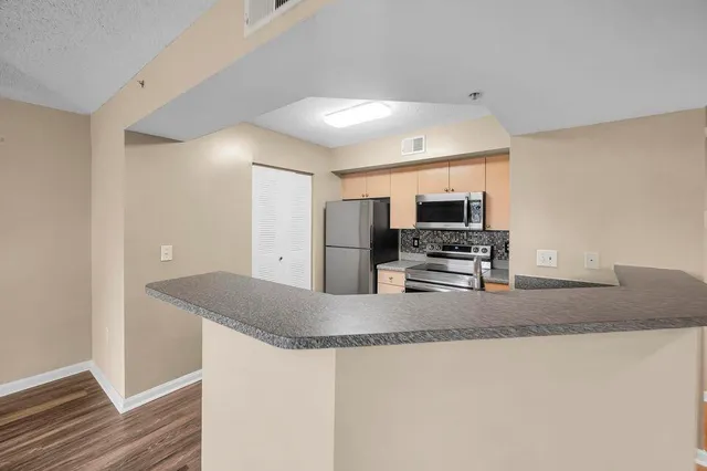 a kitchen with stainless steel appliances granite countertop a sink a stove and a refrigerator