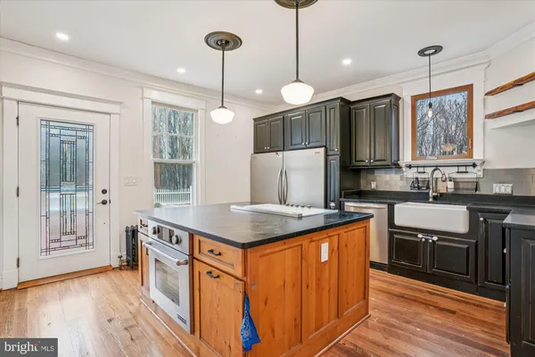 a view of kitchen with stainless steel appliances granite countertop a stove top oven a sink and a wooden floor