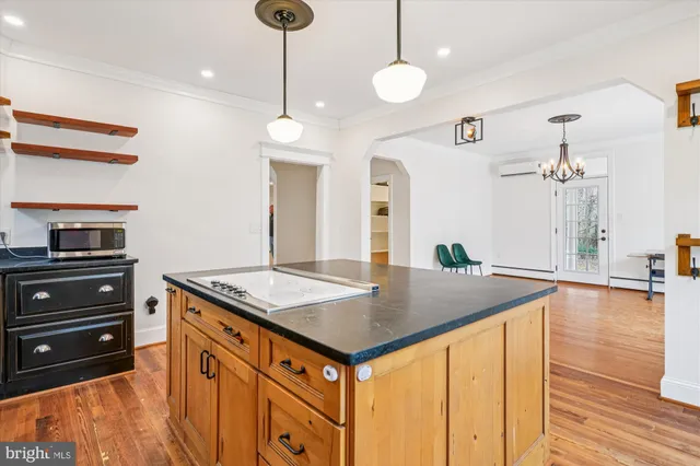 a kitchen with kitchen island stainless steel appliances a stove center island with wooden floor and cabinets