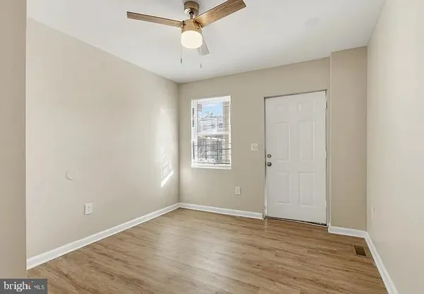 an empty room with wooden floor fan and windows