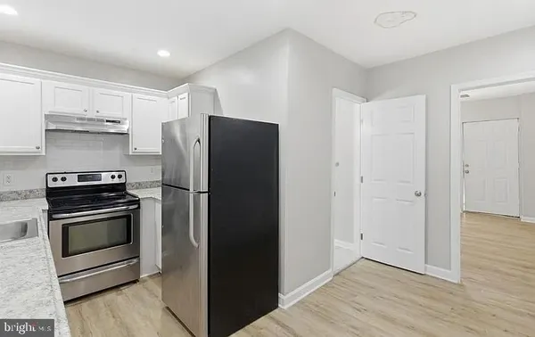 a kitchen with a refrigerator stove and wooden cabinets