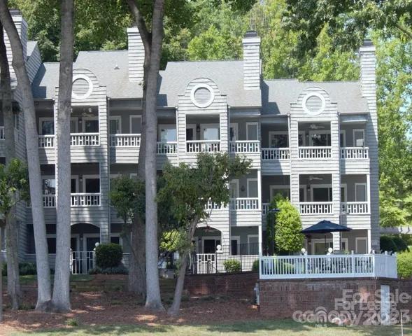 a front view of a building with a yard and large tree