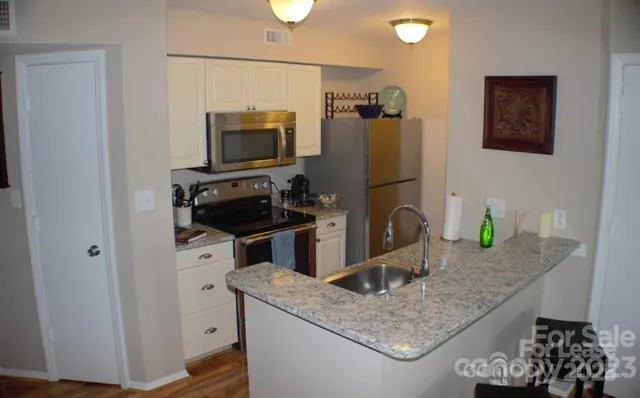 a kitchen with granite countertop a sink a stove and a wooden floor
