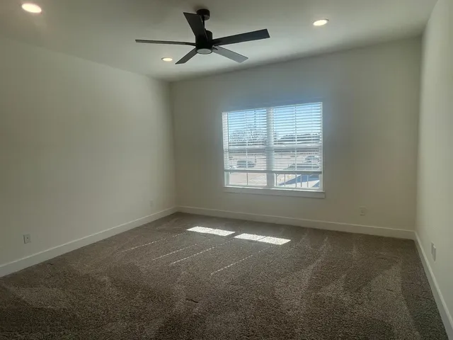 en empty room with windows and ceiling fan