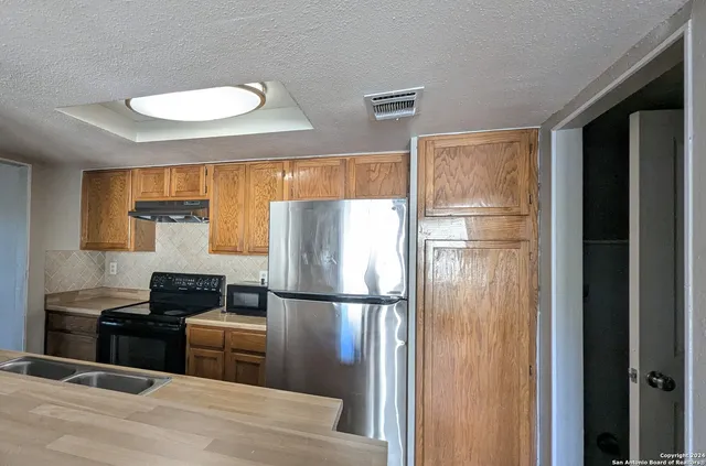 a kitchen with granite countertop a refrigerator and a stove top oven