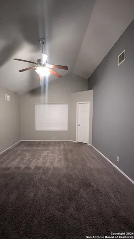 a view of an empty room with a chandelier fan