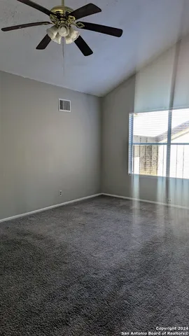 an empty room with a window and a ceiling fan