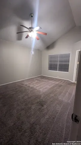 an empty room with windows and fan