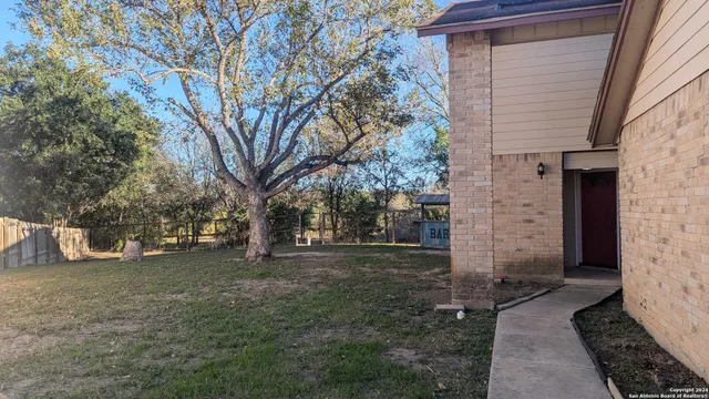 a view of a backyard with brick wall and a large tree