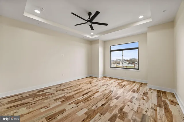 a view of empty room with wooden floor and ceiling fan