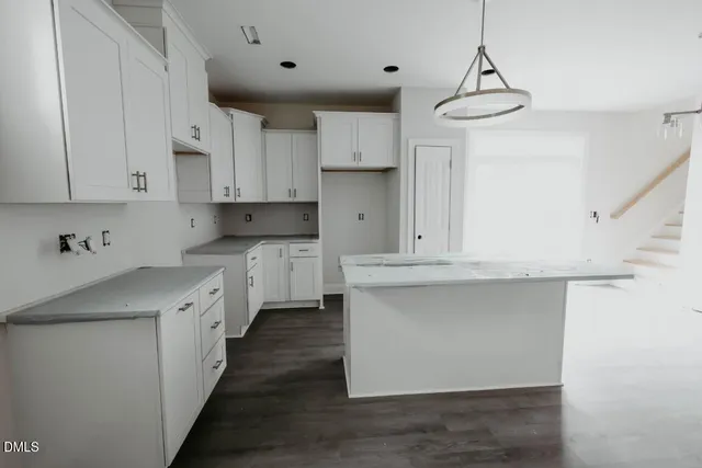 a kitchen with kitchen island granite countertop a sink a counter space and cabinets