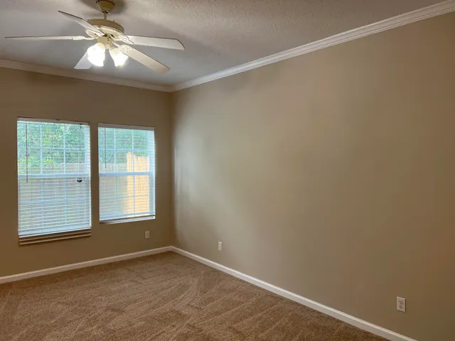 an empty room with windows and fan